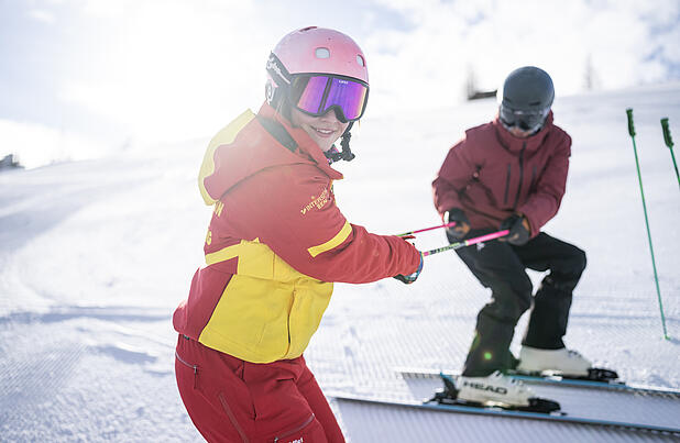 Skilehrerin unterstützt erwachsenen Teilnehmer beim Skifahren lernen in Kärnten