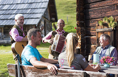 Eine Familie genießt ein Picknick auf einer blühenden Almwiese © Franz Gerdl