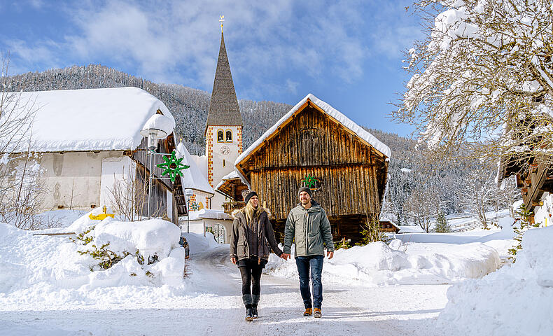 Pärchen spaziert vor einer Hütte im Schnee in Bad Kleinkirchheim