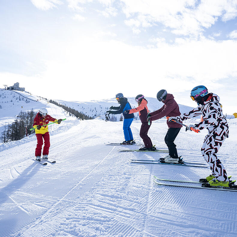 Gruppe Erwachsener übt das Skifahren mit Skilehrerin in Bad Kleinkirchheim