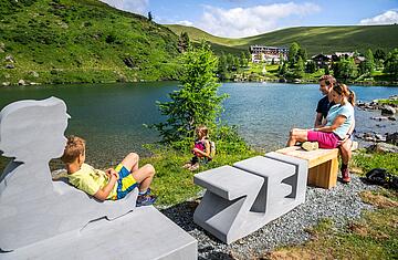 Familie genießt zusammen die Sonne auf der Zeitbank am Falkert