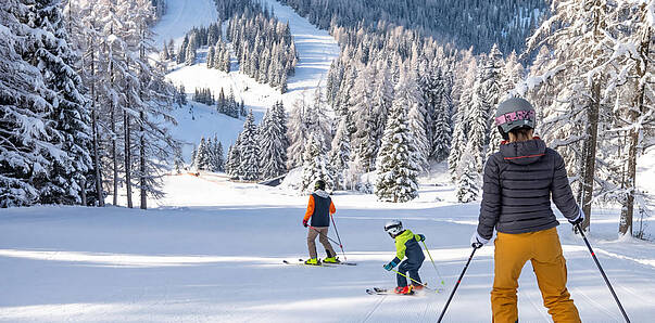 Familie beim Skifahren auf den sonnigen Pisten der Hochrindl in den Nockbergen.