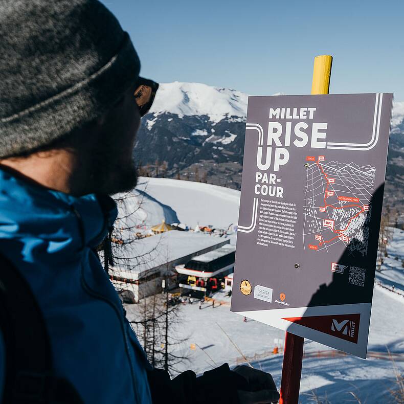 Skitourengeher blickt auf eine Tafel des Millet-Rise-Up Parcous