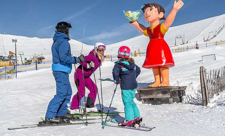 Familie steht vor Heidifigur am Falkert