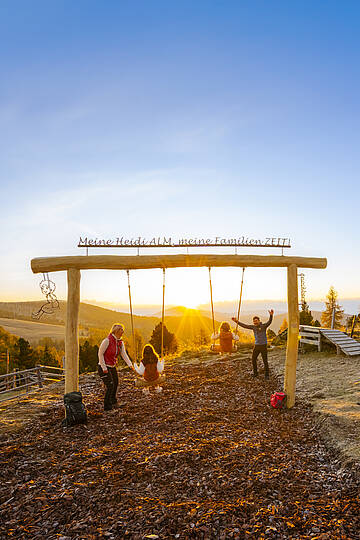 ZEITplatz mit Panoramaschaukel  im warmen Licht der untergehenden Sonne in den Nockbergen.