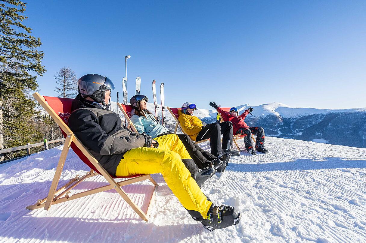 Personen sitzen in Liegestühlen und genießen die Sonne