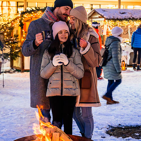 Familie wärmt sich bei einer Feuerschale am Kirchheimer Advent Markt auf