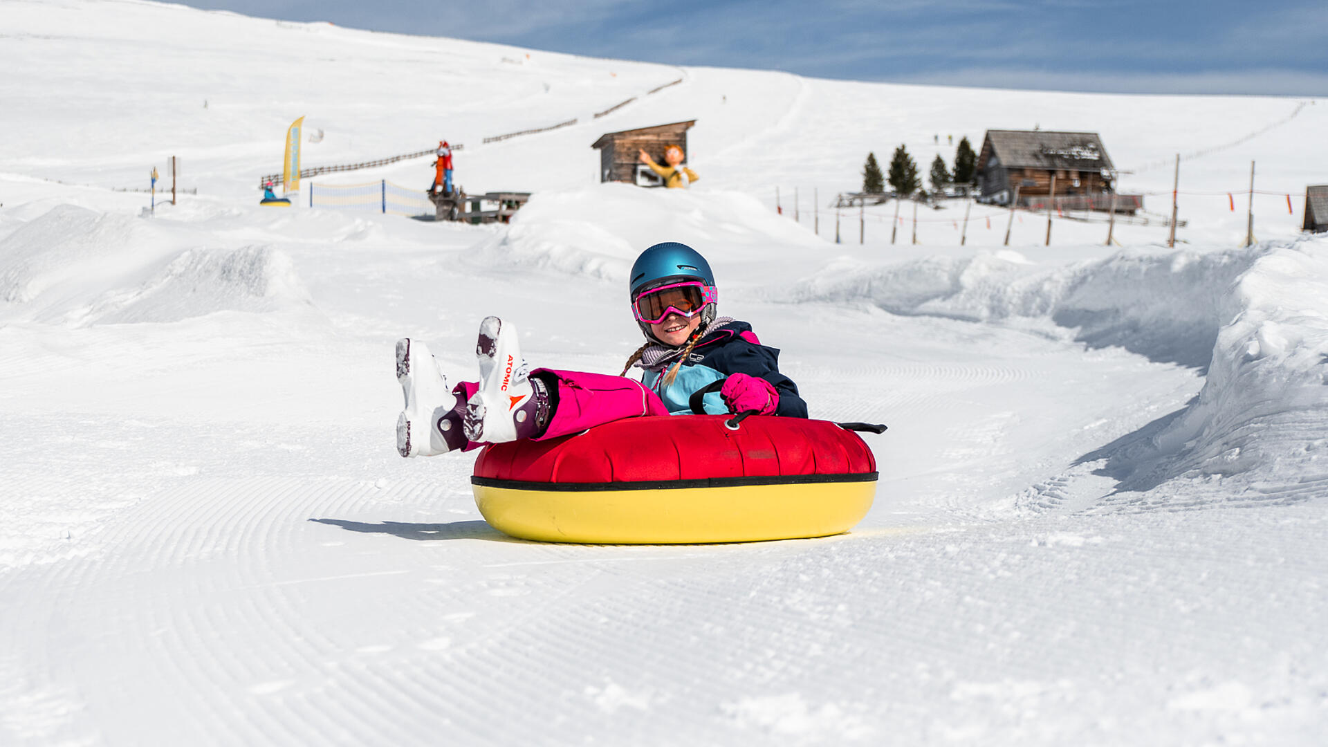 Kind fährt mit einem Tubing-Reifen den Berg hinunter