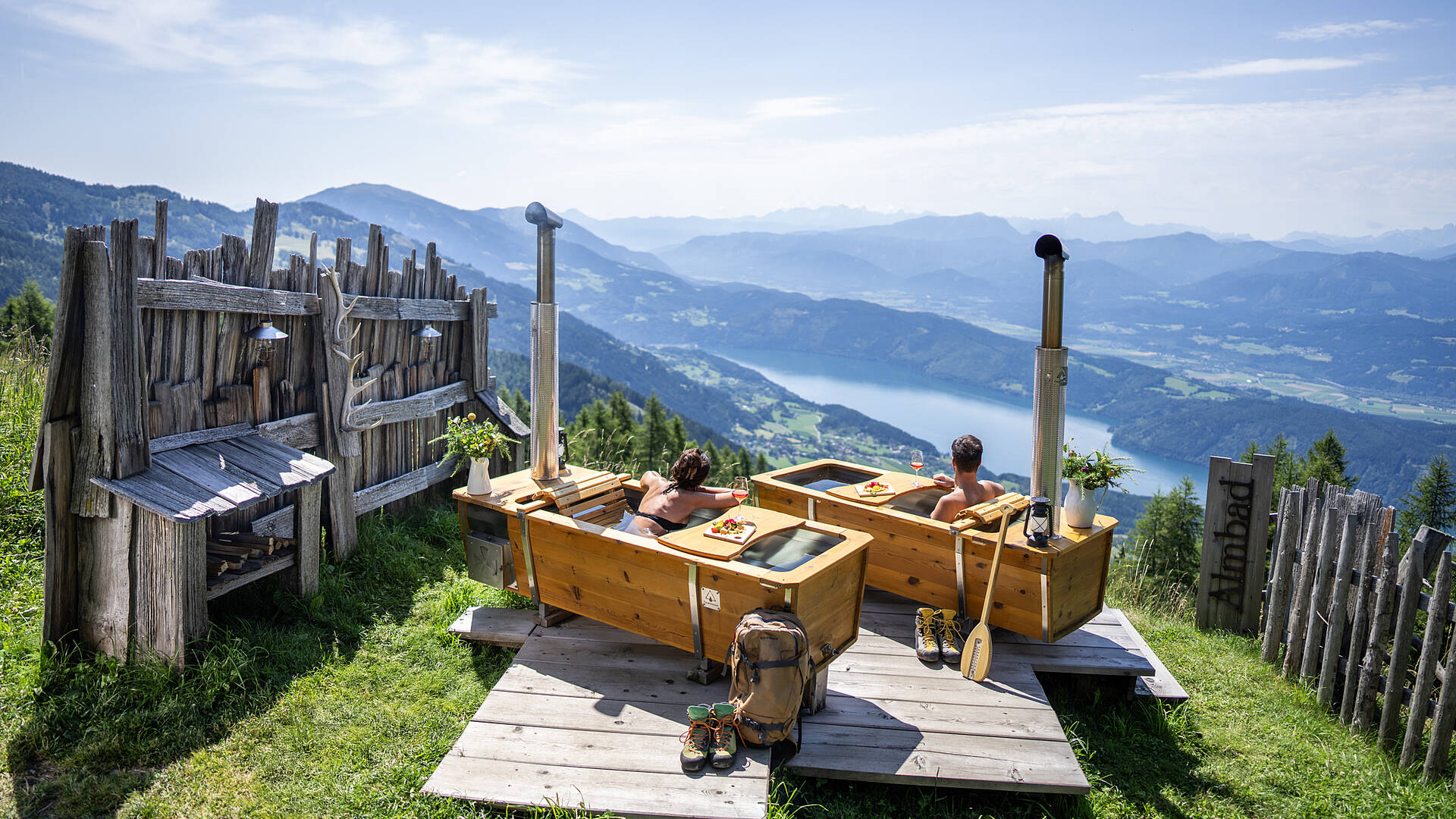 Ein Paar genießt ein AlmBad auf der AlexanderAlm mit Blick auf den Millstätter See.