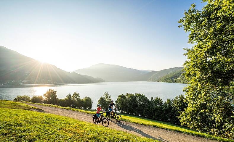 Mann und Frau fahren mit ihren Fahrrädern den Radweg am Millstätter See entlang