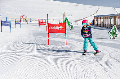 Kind fährt auf der Kinderskipiste hinunter