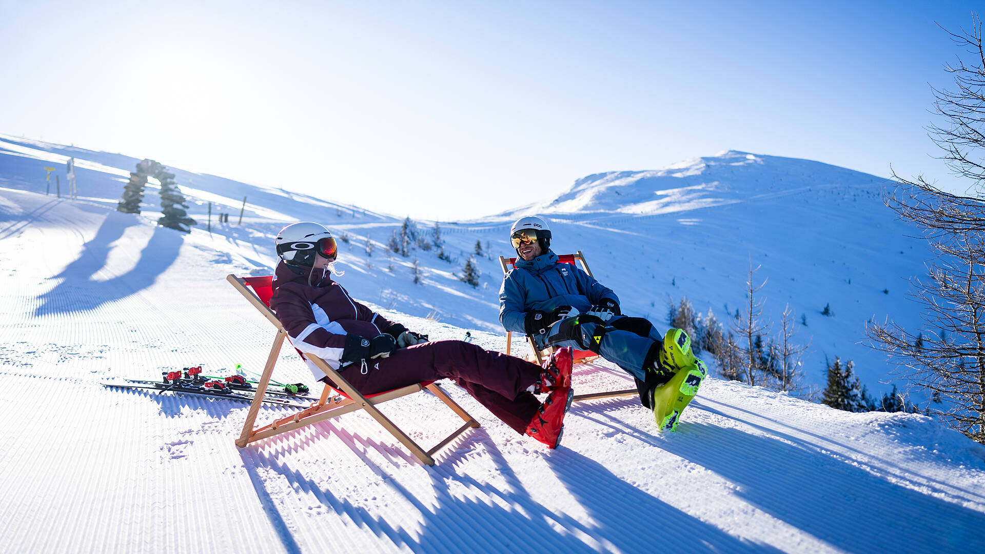 Zwei Erwachsene im Liegestuhl auf der Kaiserburg mit Wöllaner Nock im Hintergrund im Skigebiet Bad Kleinkirchheim