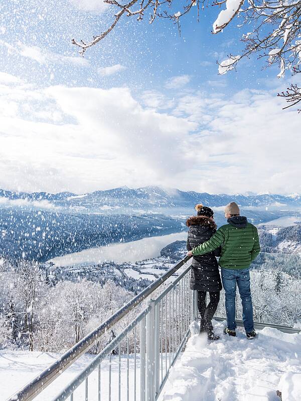 Pärchen steht im Winter am Sternenbalkon und schaut auf den Millstätter See