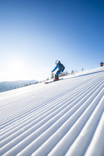 Skifahrer:innen auf einer breiten Piste im Skigebiet Bad Kleinkirchheim in den Kärntner Nockbergen