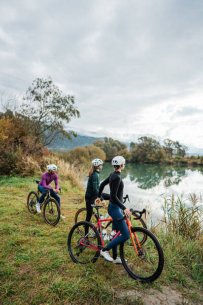 3 Personen machen eine Pause an der Drau