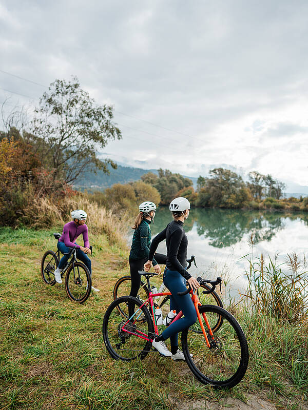 3 Personen machen eine Pause an der Drau