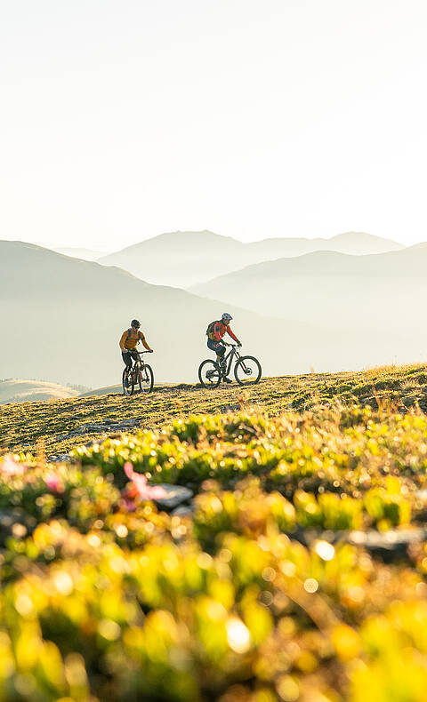 2 Personen radeln in den Nockbergen einen Gipfel hinauf