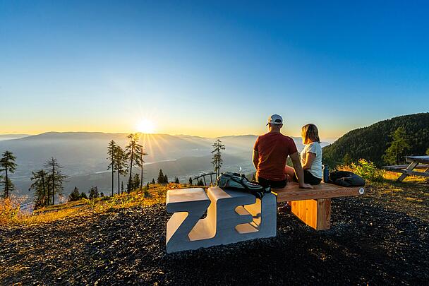 Pärchen sitzt auf Zeitbank am Goldeck und genießt den Ausblick